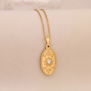 Detailed close-up of gold stainless steel celestial pendant with sun and moon engraving