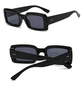 Detail view of black rectangular sunglasses with wide frames and gold dot accents
