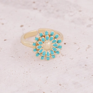 Adjustable gold ring with turquoise daisy flower petals on a textured stone surface