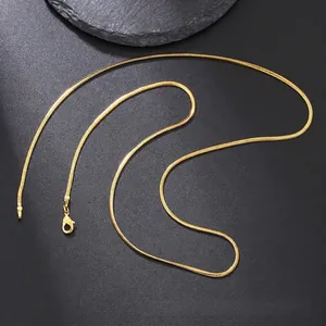 Detail of golden stainless steel snake chain with lobster clasp on a dark surface