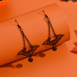 Detail of gothic black bat earrings with red eyes, chains and faceted beads on orange