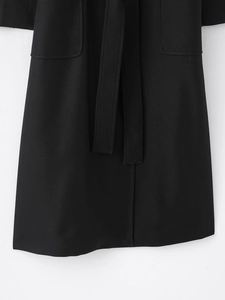 Detailed view of black wool-blend coat featuring twill texture and waist belt tie detail