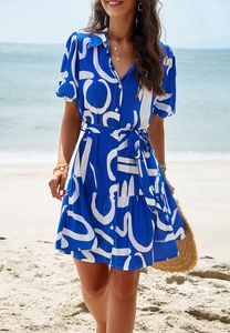 Short puff sleeve shirt dress with blue geometric pattern and tied waist at sunny beach