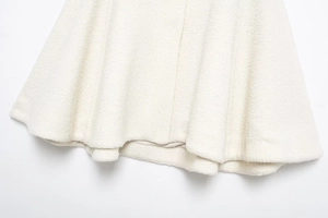 Macro view of the cream-colored bouclé fabric texture and stitching detail on women's cape