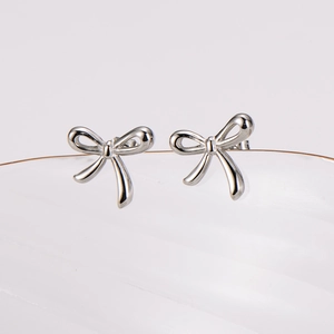 Elegant French style bow stud earrings in polished stainless steel on a white surface