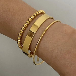 Dettaglio del set di tre bracciali rigidi e con perline in acciaio inossidabile placcato oro 18k