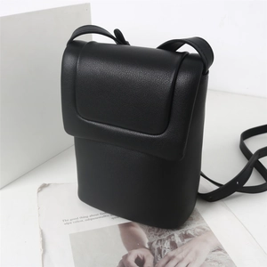 Détail du sac à téléphone noir en cuir PU texturé posé sur un journal de mode vintage