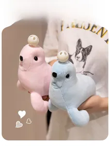 Close-up of soft pink and blue plush seal toys with decorative white ball accessories