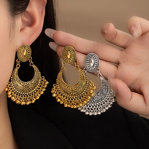 Detail view of Bohemian tassel earrings with intricate flower carvings and metallic beads