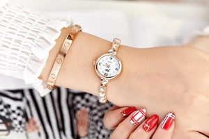 Close-up of a gold-tone women's bracelet watch with heart-shaped links and crystal accents