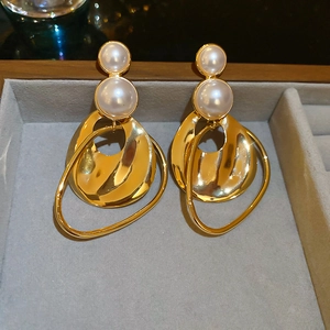 Detailed macro view of irregular gold pearl earrings in a gray velvet jewelry box