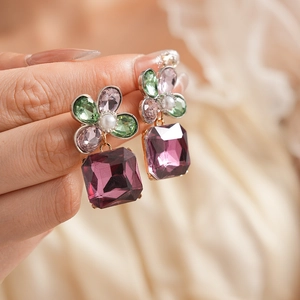 Macro shot of vintage flower earrings with square purple gemstones and pearl detail