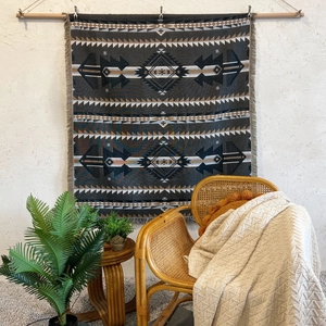Detailed view of dark grey bohemian woven blanket with geometric patterns and fringe