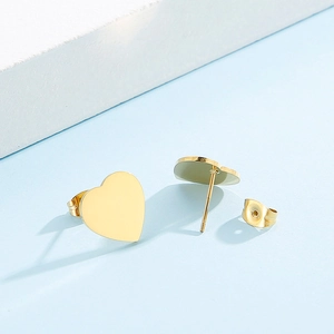 Detailed view of gold heart stud earrings with white shell on a soft blue background