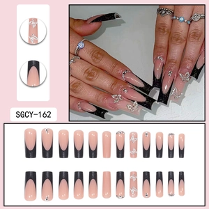 Long nude press-on nails with black French tips, silver glitter butterflies and rhinestones