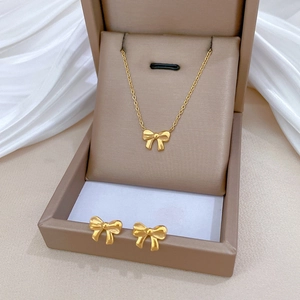 Elegant gold bow necklace and earring set displayed in a beige jewelry gift box