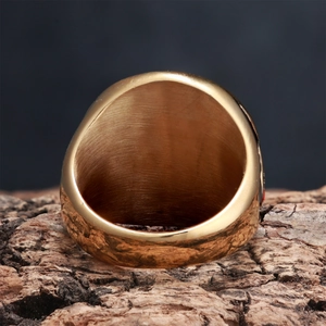 Macro shot of gold vintage shield ring on tree bark with brushed metal texture