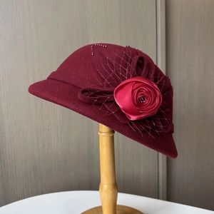 Detail eines weinroten Wollfilzhutes mit handgefertigter Satinblume und feinem Netzbesatz