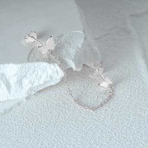 Close-up of S925 sterling silver butterfly chain earrings on white stone display