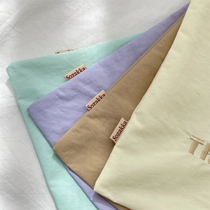 Detailed close-up of pastel cotton drawstring storage bags with brand labels and embroidery