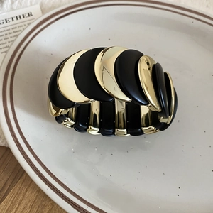 Close-up of golden metal and black matte moon-shaped segments on a chic stretch bracelet