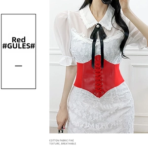 Detail of red lace-up corset belt with crisscross strings on white lace dress