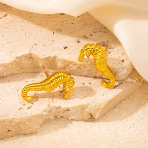 Macro shot of French vintage seahorse stud earrings with gold texture and white zircon eye