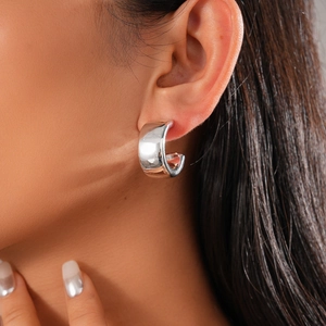 Close-up of chunky C-shape hoop earring in polished silver finish worn by a model