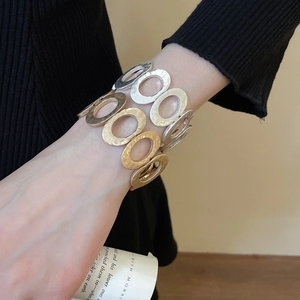 Close-up of a wide cuff bracelet with a hammered texture and oval linked patterns