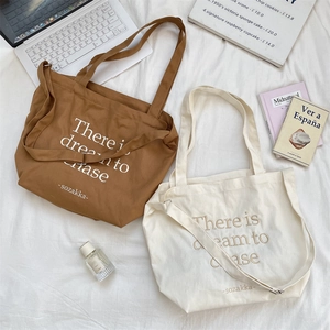 Flat lay of canvas tote bags in caramel and cream colors with adjustable crossbody straps
