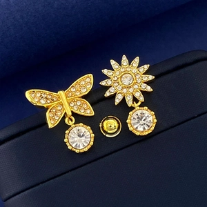 Macro shot of asymmetric gold-plated butterfly and sun stud earrings with clear crystals