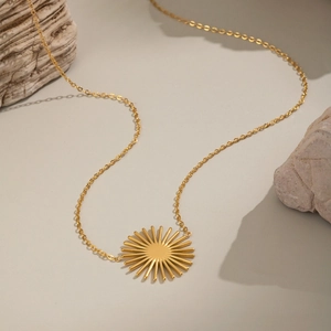 Collier minimaliste avec pendentif soleil doré et chaîne fine sur décor en pierre