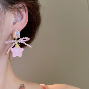 Detail of pink bow and star earrings featuring synthetic pearls and crystals