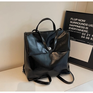 Detail of vintage black faux leather backpack featuring glossy texture and top handle design