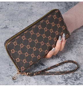Détail du portefeuille long en cuir marron avec motifs orange et dragonne assortie