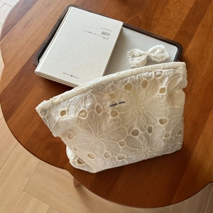 Close-up of white lace makeup bag with floral embroidery and simple wish label