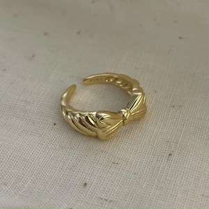 Close-up of golden bow knot S925 sterling silver ring with twisted rope texture band