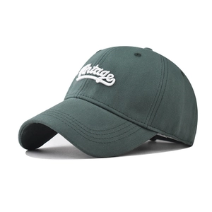 Detailed view of 3D vintage script embroidery on dark green cotton baseball cap