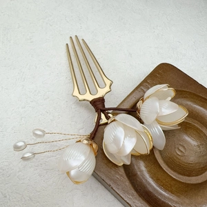 Détail du peigne à cheveux magnolia blanc avec broches dorées et perles élégantes