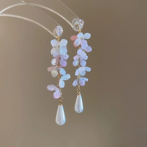 Detail of floral tassel earrings with pink acrylic petals and white pear-shaped pearl