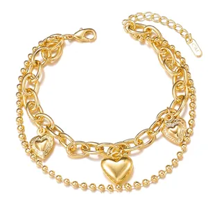 Detail of layered gold bracelet featuring round beads, link chain, and heart-shaped charms