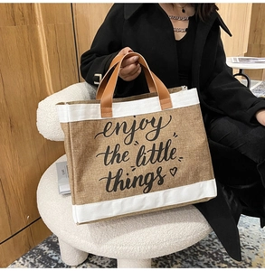 Dettaglio borsa in lino con testo enjoy the little things e manici in pelle marrone