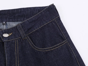 Détail d'un jean bleu foncé avec coutures jaunes contrastées et étiquette taille XS