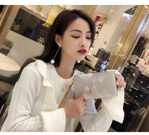 Silver woven satin evening clutch bag held by model with matching pearl earrings