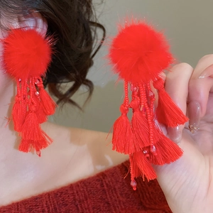 Close-up of elegant red fur ball earrings with long tassel drops and beads