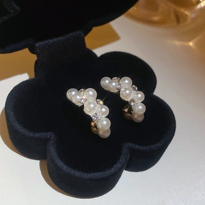 Macro view of crystal and pearl drop earrings displayed in a black velvet gift box
