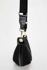 Detail of black woven shoulder bag with leather accents and gold-tone metal hardware