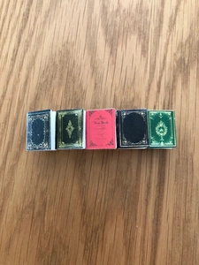 Detailed macro view of five miniature notebook hair clips in assorted retro colors on wood