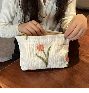 Detail of embroidered tulip pattern on white textured fabric makeup organizer bag