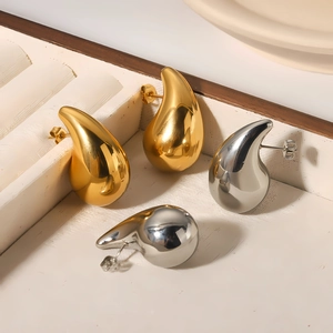 Polished gold and silver teardrop hollow earrings displayed in a luxury jewelry box